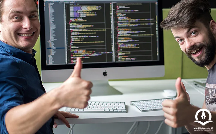 در این تصویر دو برنامه نویس مرد در مقابل کامپیوتری که کدهای برنامه نویسی بر روی صفحه مانیتور آن نمایش داده شده است، قرار دارند و گویا در کمپ برنامه نویسی شرکت کرده اند